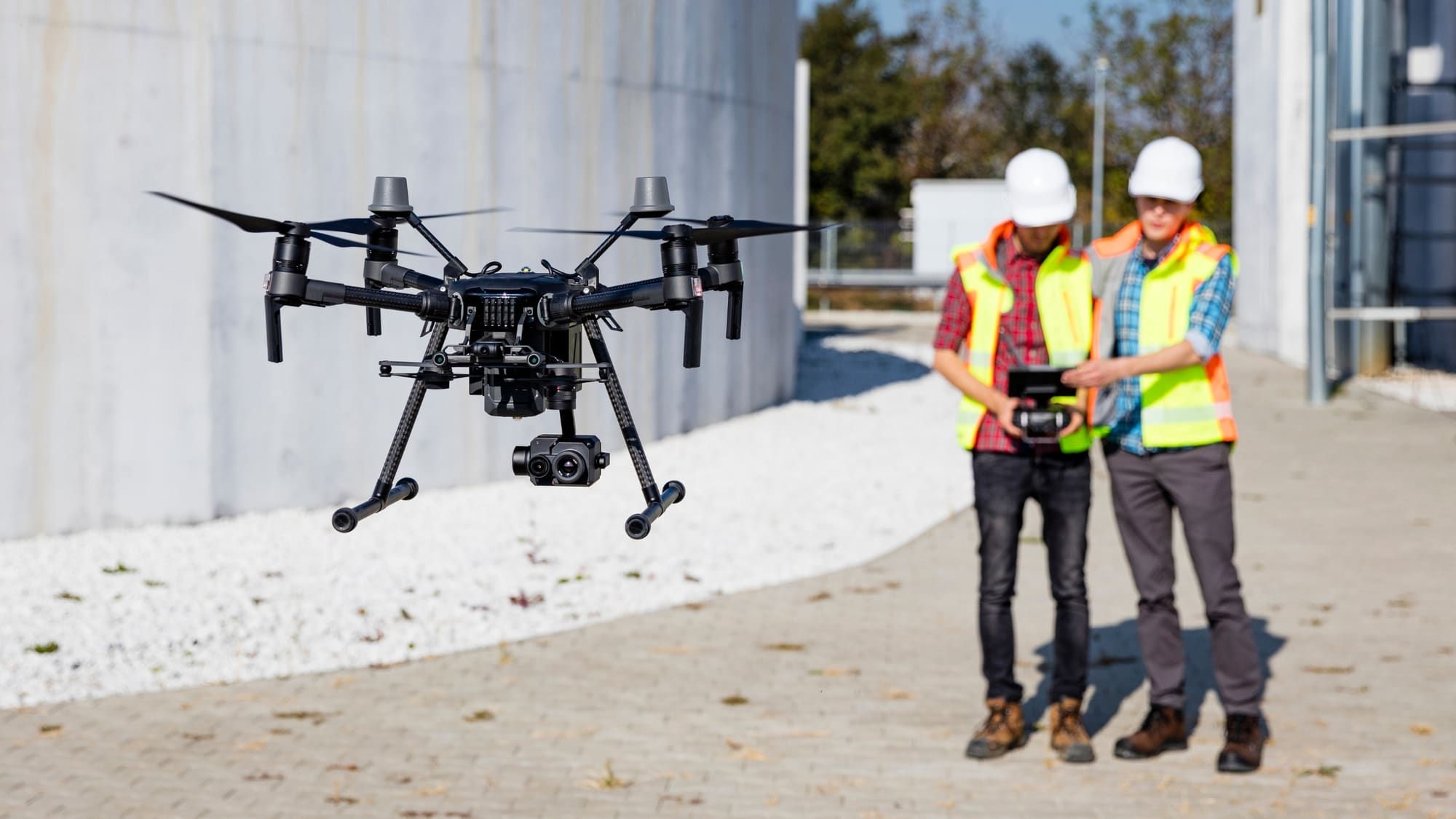 Drone pilots in safety vests flying an industrial inspection drone on site
