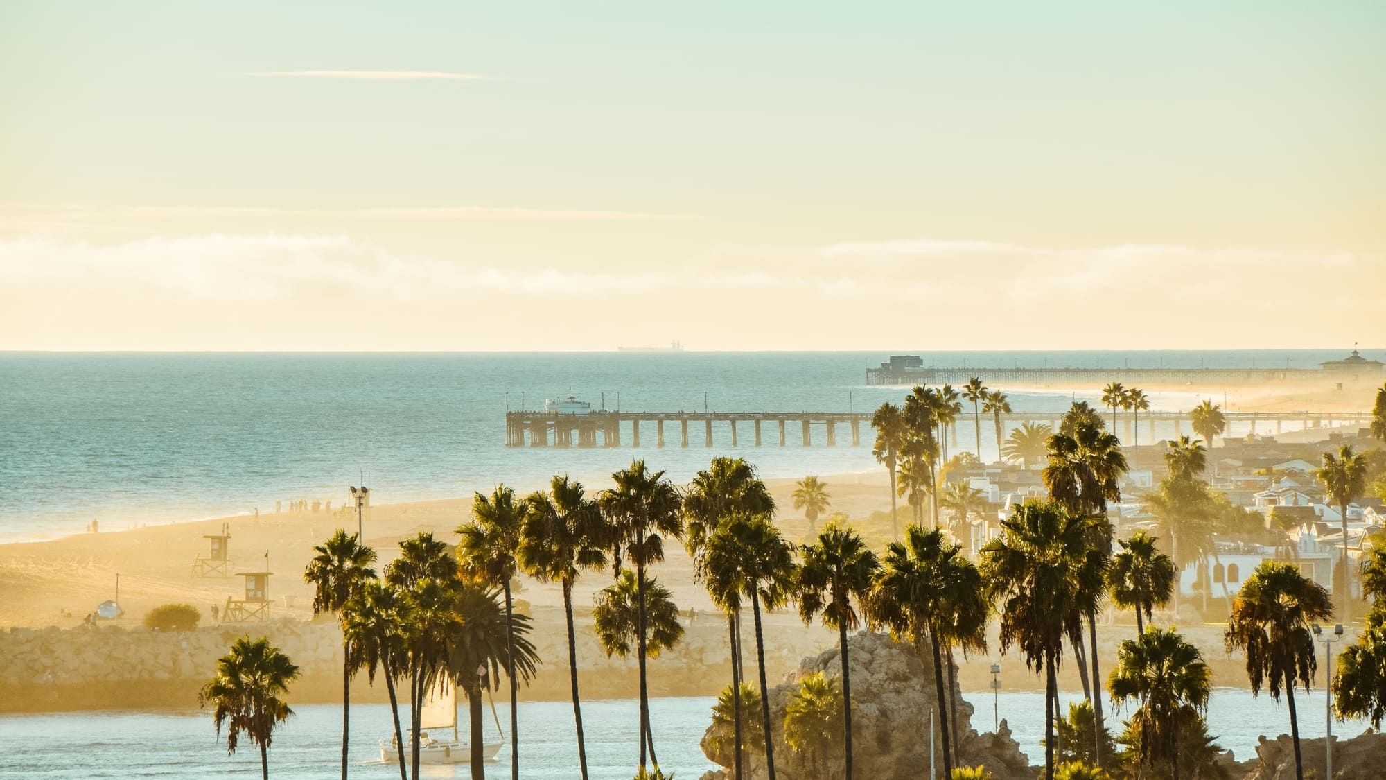 Golden-hour drone photo of the Newport Beach pier and palm trees in Orange County