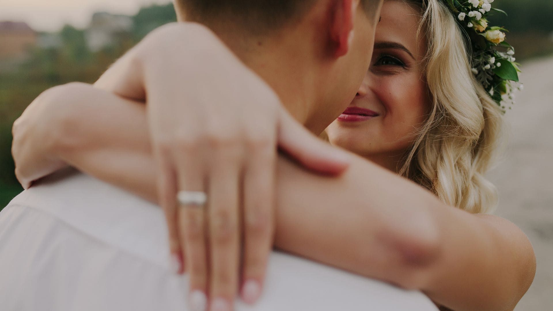 Bride with flower crown embracing groom during golden-hour wedding portraits